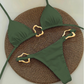 Green bikini set with gold straps on a textured brown mat