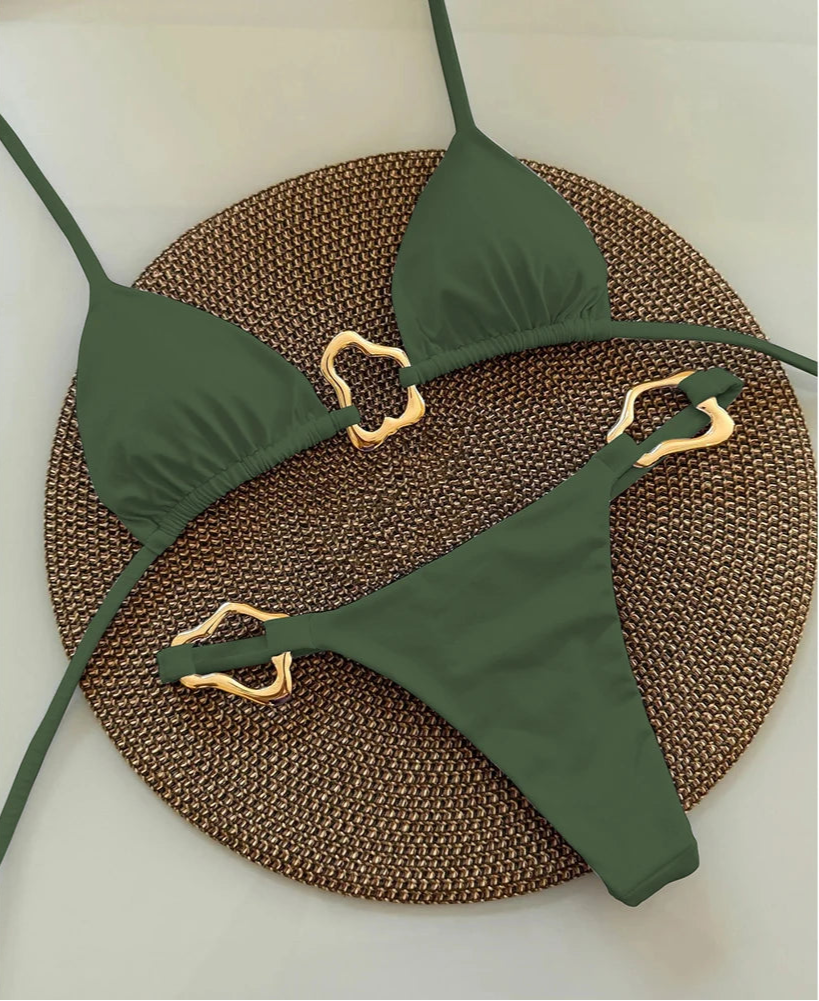 Green bikini set with gold straps on a textured brown mat