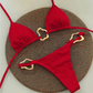 Red bikini set with gold straps on a textured brown mat