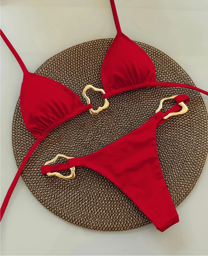 Red bikini set with gold straps on a textured brown mat