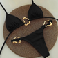 Black bikini set with gold accents on a textured brown surface