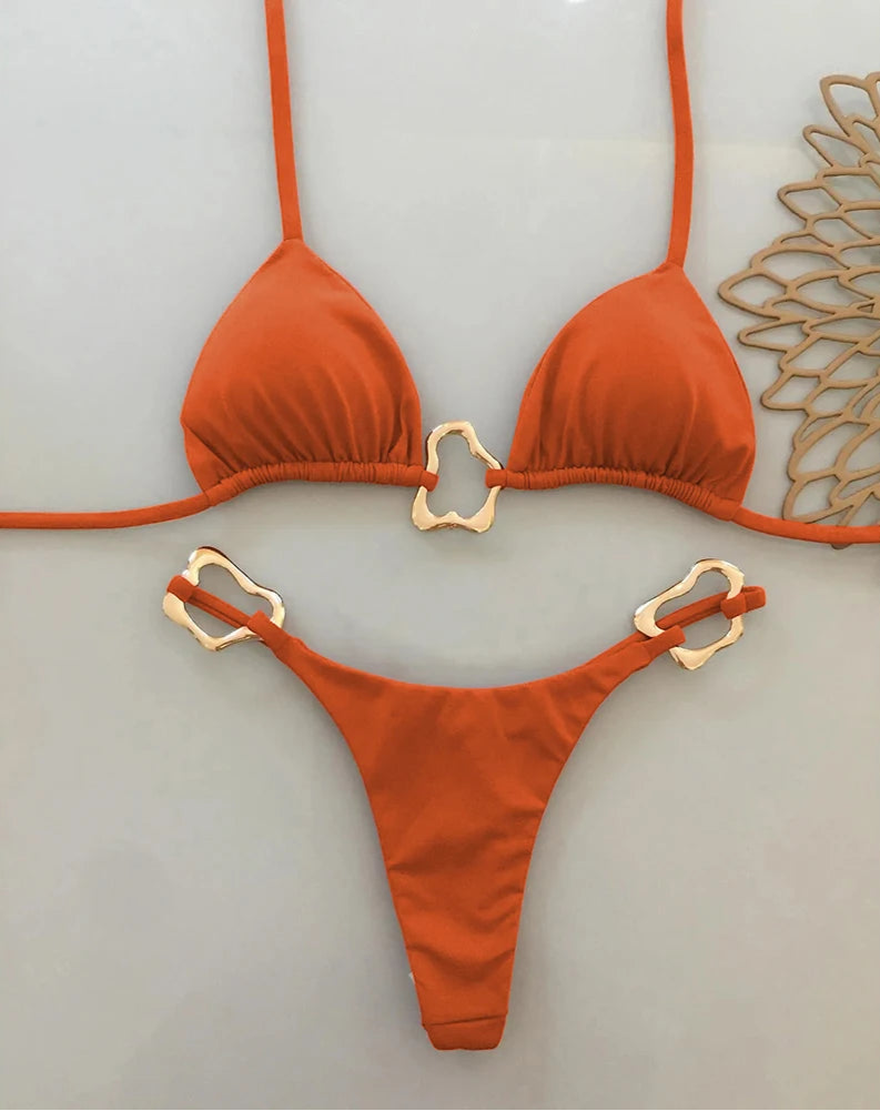 Orange bikini set with gold hardware on a light gray background