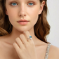 Close-up of a woman wearing a ring with a blue gemstone on a plain background