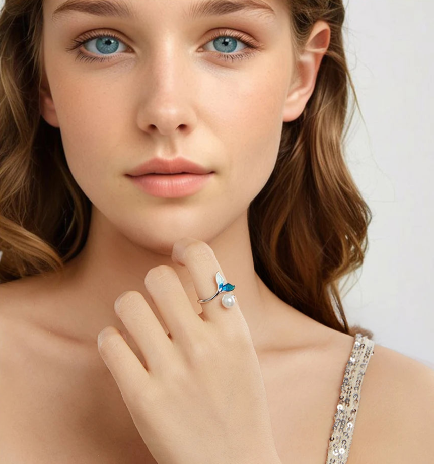 Close-up of a woman wearing a ring with a blue gemstone on a plain background
