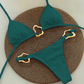 Teal bikini set with gold hardware on a textured brown surface